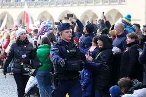 policjant reguluje ruch pieszych na rynku przed pochodem