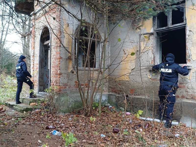 Policjantka wchodzi do opuszczonego domu, a drugi policjant zagląda do środka budynku przez wybite okno.