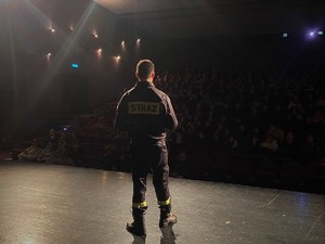 strażak podczas wystąpienia w sali kinowej