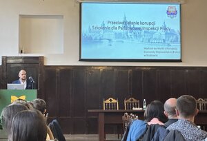 uczestnicy szkolenia przy stołach, prelegent przy pulpicie