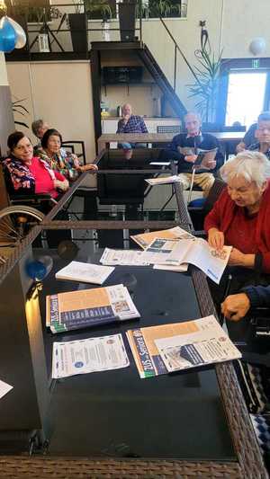 seniorzy przeglądają ulotki edukacyjne