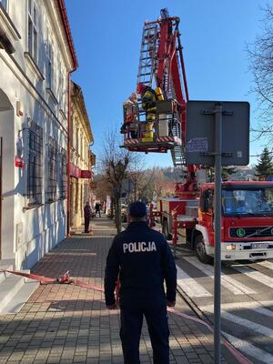Umunudrowany policjant oraz wóz strażacki podczas działań związanych z uwolnieniem osoby