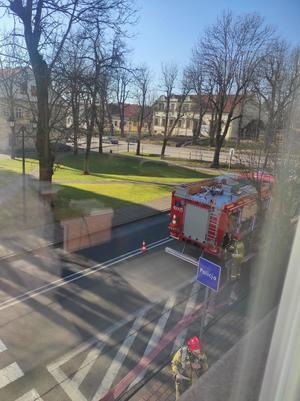 Wóz strażacki, strażak biorący udział w akcji oraz tablica z napisem policja