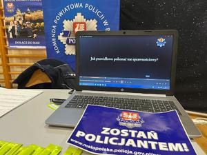 laptop z otwartym filmem jak pokonać tor sprawnościowy, na nim ulotka zostań policjantem