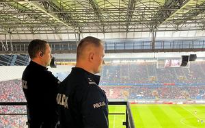 Zastępca Komendanta Miejskiego Policji w Krakowie w towarzystwie innego policjanta w czasie meczu obserwują sytuacje na trybunch na jednym z krakowskich stadionów