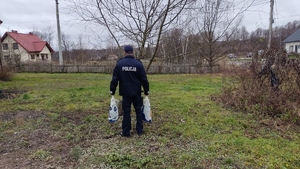 Policjant niosący torby z pomocą świateczną