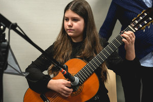 dziecko gające kolędę na gitarze