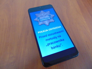 telefon z napisem policja ostrzega przed oszustwami metodą na pracownika banku