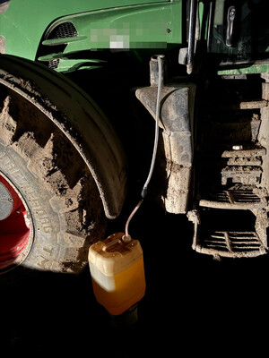 bak maszyny budowlanej, z której spuszczane jest paliwo do kanistra