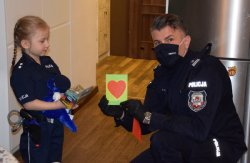 1 Komendant Miejski Policji w krakowie wręcza dziewczynce kartkę okolicznościową z sercem