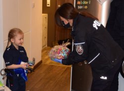 policjantka wręcza dziewczynce paczkę słodyczy