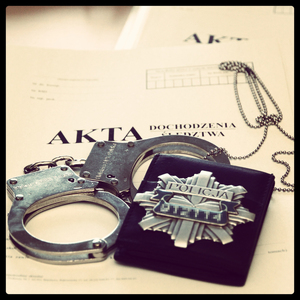 kajdanki i odznaka policyjna na teczce akt sprawy