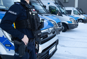 Funkcjonariusz-OPP-stojący-na-tle-samochodów-w-kamizelce-kuloodpornej.