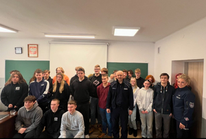 umundurowani policjanci na prelekcji w szkole w tle uczniowie szkoły