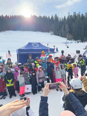Komendant w otoczeniu dzieci na tle namiotu policyjnego
