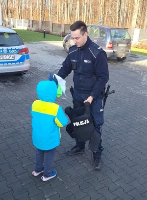 policjant pokazuje chłopcu elementy umundurowania służbowego