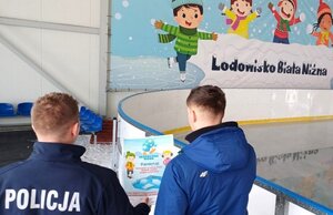 policjant przekazuje ulotkę edukacyjną na lodowisku
