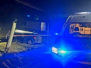 samochód marki kia na który przewrócił się słup energetyczny, a obok policyjny radiowóz