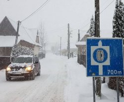 zaśnieżona droga i zimowe znaki drogowe na poboczu