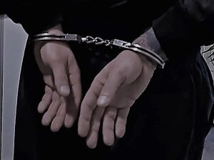 Kajdanki policyjne założone na ręce trzymane z tyłu