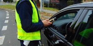 KPP Oświęcim. Kontrola trzeźwość badanie  policjant obok samochodu z alcoblow w ręce