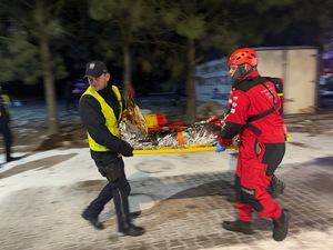 policjant i ratownik niosący poszkodowanego