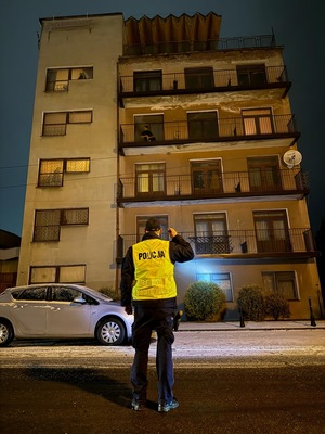 policjant oświetlający budynek latatką