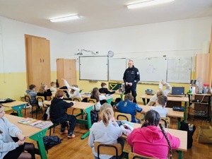 9.Policjant wraz z uczniami podnoszącymi ręce do pytania podczas zajęc o bezpiecznym internecie