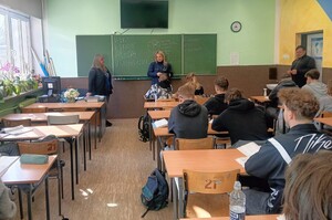 umundurowana policjantka w klasie szkolnej rozmawia z uczniami klasy maturalnej na temat służby w Policji.