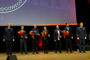 Ambasadorzy bezpieczeństwa ruchu drogowego stoją z kwiatami oraz statuetkami obok policjanci, komendant oraz naczelnik