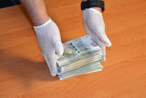 funkcjonariusz  układa zabezpieczone banknoty w stosie