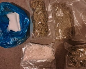 Po lewej stronie w niebieskim worku proszek koloru białegeo w woreczku, po prawej dwa woreczki z suszem, a poniżej w woreczku substancja krystaliczna i obok w woreczku susz.