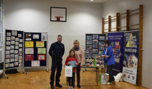 Umunudrowany policjant, dyrekcja szkoły oraz uczennica odbierająca nagrodę