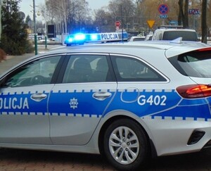 Radiowóz przy ulicy z włączonymi sygnałami uprzywilejowania