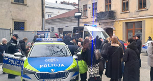mieszkańcy biorący udział w spotkaniu przy bazylice, obok policyjne radiowozy