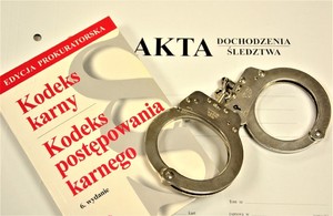 Na teczce z napisem Akta dochodzenia śledztwa leżą kajdanki i kodeks postępowania karnego.