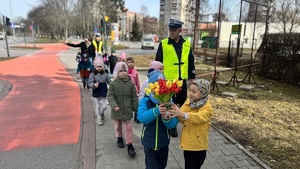 dzieci z kwiatami i policjanci zmierzający na wspólne działania