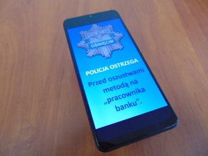 KPP Oświęcim. Telefon z napisem policja ostrzega przed oszustwami metodą na pracownika banku