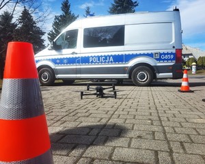 Oznakowany radiowóz, przed nim  startujący dron policyjny