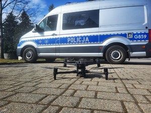 Policyjny dron, obok oznakowany radiowóz