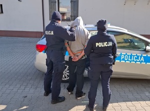 KPP Oświęcim. Policjant i policjantka z zatrzymanym obok radiowozu