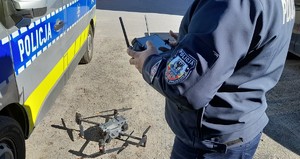 Policjant oraz policyjny dron obok radiowozu