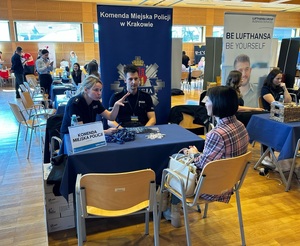 Policjanci rozmawiaja z potencjalną kandydatką na swoim stoisku podczas targów