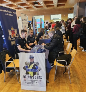 Policjanci rozmawiaja z potencjalnym kandydatem na swoim stoisku podczas targów