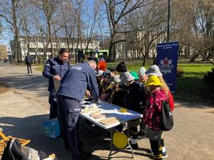 Policyjne stoisko a przy nim  stoi grupka dzieci i dwaj umundurowani policjanci