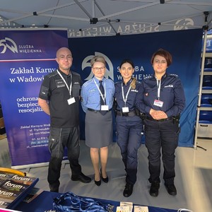 Po prawej stronie dwie umundurowane policjantki, a po lewej funkcjonariuszka i funkcjonariusz Zakładu Karnego w Wadowicach. W tle rozłożone banery.