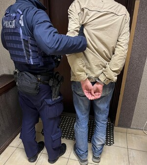 Policjant prowadzi zatrzymanego sprawcę pobicia