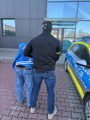 Nieumundurowany policjant trzyma zatrzymanego męzczyznę