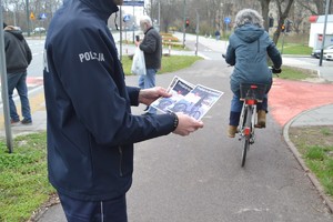 Policjant trzyma w rękach ulotki przejście to nie przejazd