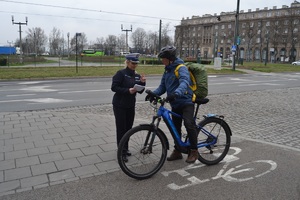 Policjantka przy drodze dla rowerów omawia rowerzyście zasady ruchu drogowego